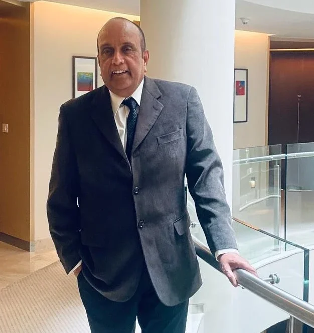 "Professional businessman in grey suit and blue tie standing in modern office hallway"