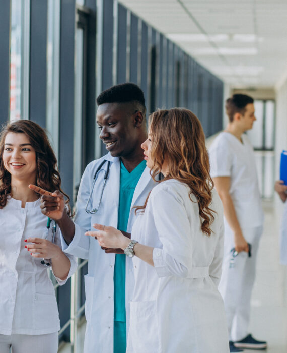"Diverse medical residents discussing patient charts in modern hospital corridor"